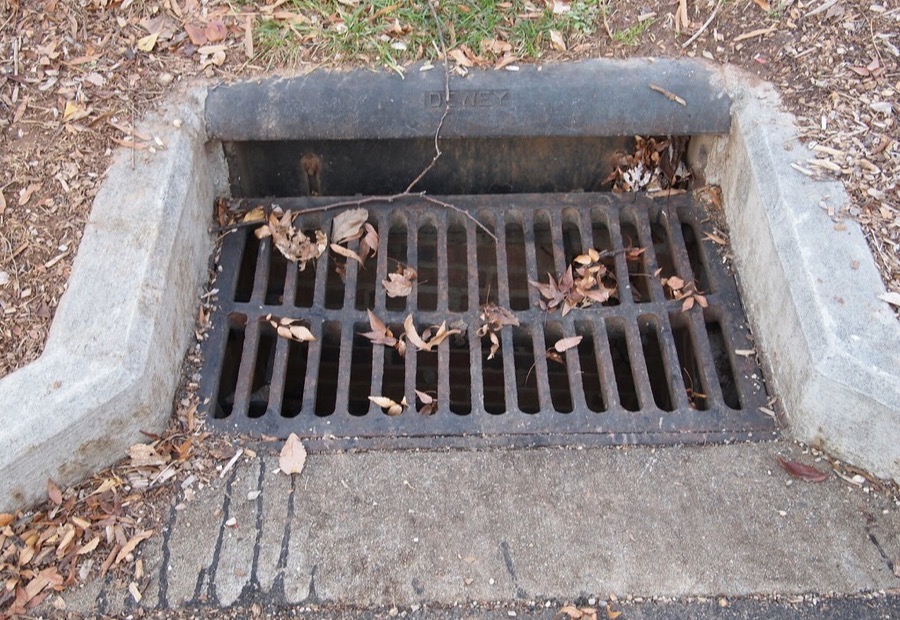 Catch basin box with a grate set at a low point beside a buried dry well