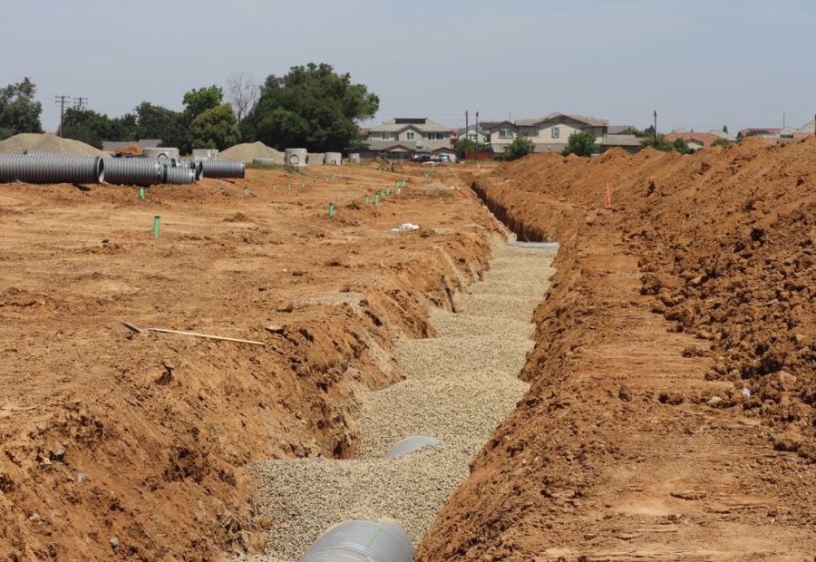 Exterior footing drain tile in stone along an excavated foundation wall