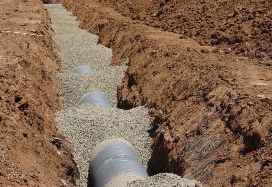 Perforated french drain pipe in washed stone lined with filter fabric in a trench